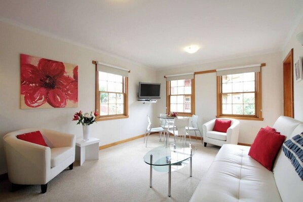 The living and dining area has plenty of seating for relaxation and dining, along with a wall-mounted TV for entertainment.