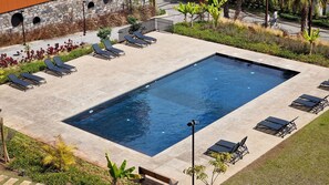 Spacious condominium pool area with comfortable sun loungers, perfect for relaxing under the sun. Surrounded by greenery and offering a peaceful atmosphere for a refreshing swim or lounging. #pool #luxsuite