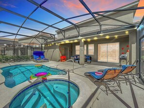 Pool with sun lingers and patio in a glass enclosure