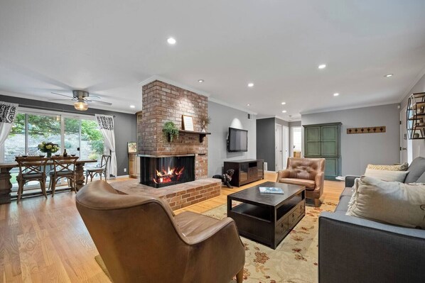 Cozy living room, comfortable sofa, luxurious leather chairs, real wood burning fireplace 