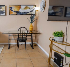 A dedicated workspace or small dining nook with a glass-top table, a black chair, and a charming pineapple decor piece.