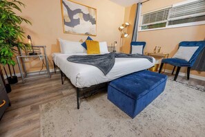 Plush bed, a blue ottoman at its foot, and coordinating accent chairs.