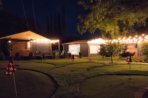 Outdoor Patio with String Lights and Projector Screen: "Transform your evenings into a cinematic experience with our outdoor patio, featuring ambient string lights and a large projector screen for unforgettable movie nights."