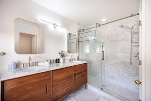 Elegant bathroom with a marble-tiled shower, double vanity, and warm wood accents