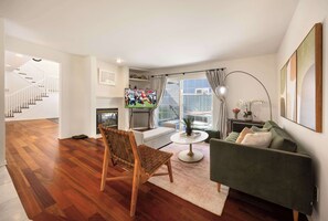 Cozy living room with a modern vibe, featuring a plush sofa, TV, and access to a sunlit balcony