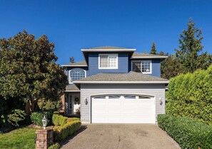 A stunning two-story home with a bright blue exterior, lush landscaping, and a welcoming front entrance for a picture-perfect stay.