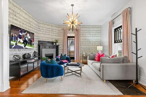 Unit 1: Living room on the first floor with a smart TV and a decorative fireplace. (1st Floor)