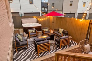 Unit 1: Fenced in back yard with firepit, seating, and a hot tub.