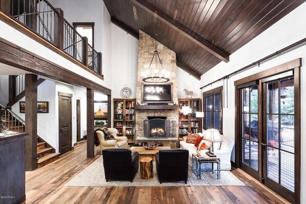 Grand Living & Dining – A soaring ceiling, stone fireplace, and open-concept elegance create a warm, inviting space perfect for gatherings.