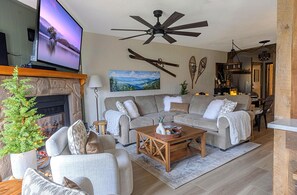 The living room greets you as you enter with an electric fireplace, 65" smart TV, and ample seating.
