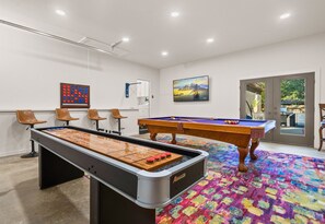 The game room is a haven for fun, featuring a shuffleboard table, pool table, and plenty of space to enjoy some friendly competition with family or friends.