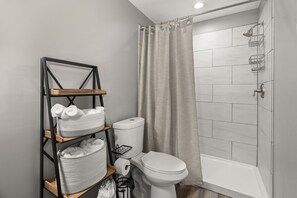This bathroom offers a sleek shower-tub combo with organized shelving design.