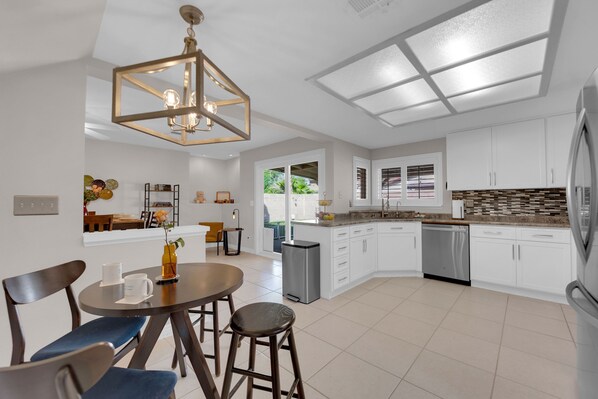 The main level boasts a beautifully upgraded eat-in kitchen, complete with crisp white cabinetry, modern stainless steel appliances, and generous counter space that makes cooking effortless.