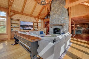 Stunning great room with a spacious sectional, large fireplace, and breathtaking panoramic views of Cannon Mountain. Perfect for relaxing with family or watching TV by the fire.