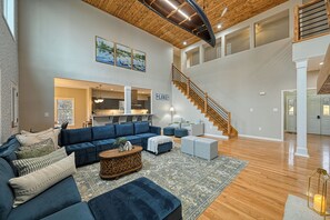 Unwind in the inviting living area, featuring spacious sectional sofa, 65-inch smart TV, and cozy gas fireplace. This bright and open space is filled with natural light from expansive picture windows, highlighting the beautiful hardwood floors. With its open-concept design, it seamlessly connects to the kitchen, dining area, and outdoor living space, making it perfect for gathe...