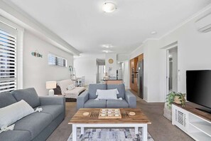 The living room is open plan with plush sofa seating and a central TV for relaxing after a busy day.
