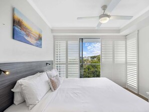 The primary bedroom, featuring a king-sized bed, offers serene views of the outdoors right from your window. The ensuite bathroom provides added convenience and comfort.