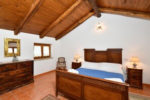 Elegant bedroom vaulted ceiling, wooden bed, AC rustic dresser, terracotta floor
