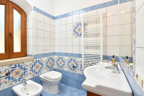 Mediterranean blue/white tile bath: shower, toilet, sink, bidet & natural light.