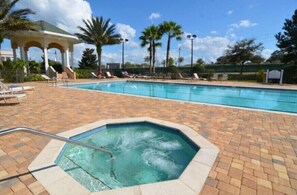 Sparkling pool and hot tub surrounded by lush greenery and ample lounging areas.