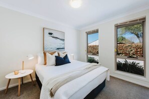 The stylish third bedroom is also set with a queen bed and flanked by side tables and reading lights.