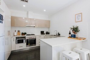 The kitchen centres around a breakfast bar where you can enjoy a casual coffee or set up your laptop and work remotely.