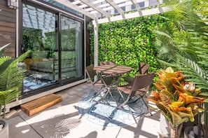 Sit on a private patio, which features four seats and is surrounded by greenery.