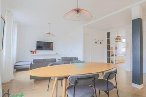 Salon avec TV HD et espace salle-à-manger, ouvert sur la cuisine. (2)