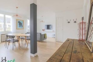Salon avec TV HD et espace salle-à-manger, ouvert sur la cuisine. (3)