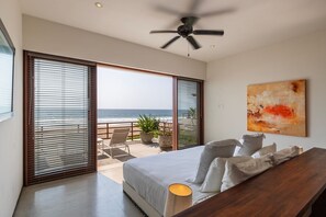 A cozy and elegant bedroom with natural light, warm wooden tones, and direct access to the terrace with ocean views.