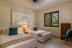 A serene twin bedroom featuring ocean-inspired decor, cozy bedding, and a window overlooking lush greenery for a peaceful retreat.
