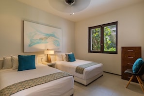A serene twin bedroom featuring ocean-inspired decor, cozy bedding, and a window overlooking lush greenery for a peaceful retreat.