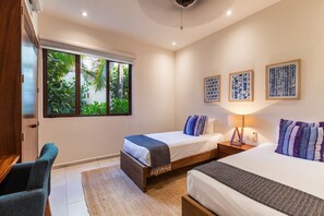 A charming twin bedroom featuring handcrafted wooden furniture, soft blue decor, and peaceful natural views.