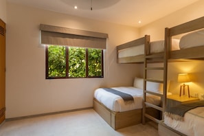 Designed for comfort and style, this spacious bunk room features built-in wooden beds, soft lighting, and a tranquil garden backdrop.