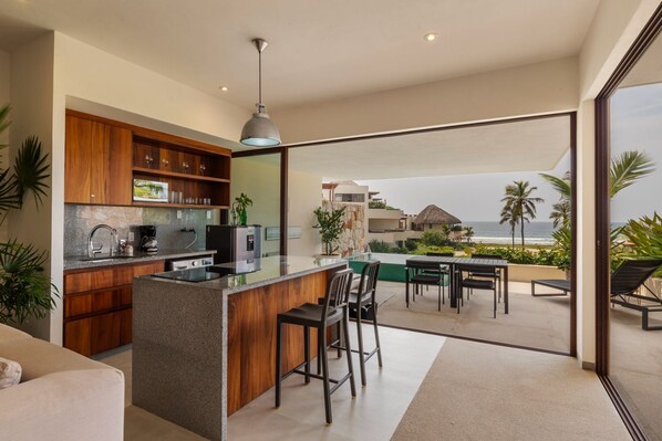 A sleek, modern kitchen with high-end appliances, wood accents, and an open layout leading to the poolside terrace.