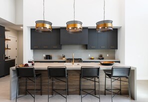 Fully equipped kitchen boasting high-end stainless steel appliances and a large island offering bar seating overlooking the formal dining area.