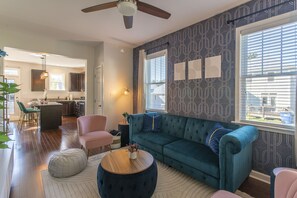 Living room with large plush couch, ceiling fan, and steps away from the dining