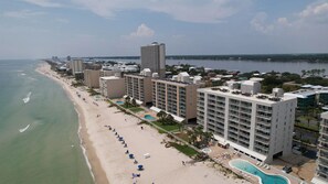 A picturesque view looking west at the building from the Gulf, showcasing its stunning beachfront location and proximity to the pristine sandy shore.