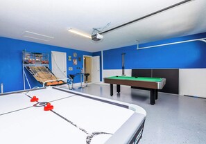 The garage has been converted into a game room with air hockey, basketball hoops, and a pool table