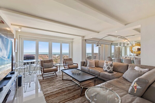 A bright and spacious living area with elegant décor, featuring plush seating and large windows that offer stunning ocean views.
