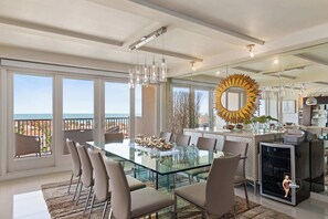 A modern dining space with a glass-top table, stylish chairs, and an open kitchen, perfect for hosting meals with family and friends.