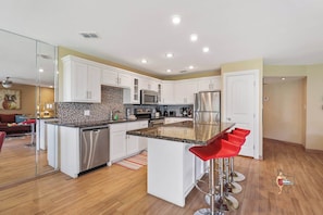 Modern kitchen with sleek countertops, white cabinetry, and high-end appliances, including a kitchen island with bar seating.