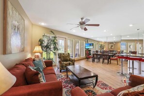 Spacious living area with cozy seating and a ceiling fan, perfect for relaxation or gathering with family and friends.