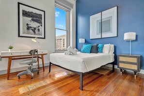 Inviting space with a comfortable bed, natural light streaming through large windows, and minimalist decor for a serene atmosphere.
