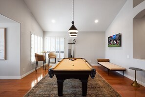 Game room with smart TV, pool table, bar table for two, and lounge chair. (1st Floor)