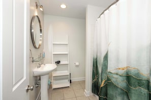 The upper-level full bath includes a pedestal sink & shower/tub combo