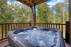 Expansive deck with a hot tub and stunning mountain views.