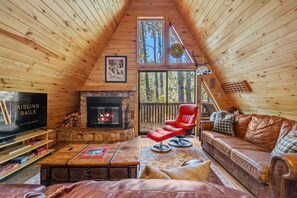 Main living room with a wood-burning fireplace, smart TV with cable and coy seating options.