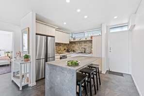 The modern kitchen features sleek appliances, including a microwave, coffee machine, dishwasher, fridge, and oven, all designed for creating special dishes. Ample counter space and stylish storage enhance functionality and elegance.