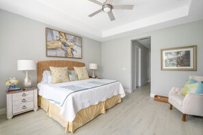 The master bedroom features a king bed with plush pillows and a cozy quilt, enhanced by a stylish nightstand and chic lamps for a luxurious touch.